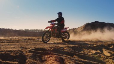 Yan görünümü görüntüleri Dune üzerinde sürüş profesyonel motokros motosiklet binici ve daha aşağı Off-Road parça. O gün batımı ve parça dumanla kaplı / toz / kir.