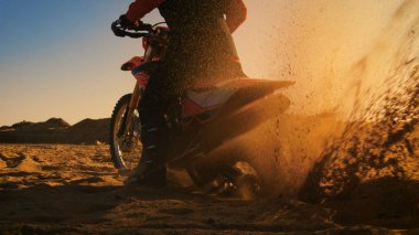 Back View Footage of the Professional Rider on the FMX Dirt Bike Twisting Full Throttle Handle and Digging into the Sand with His Back Wheel. clipart