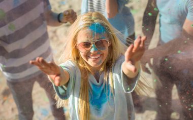 Kalabalığın ortasında Hindu Holi Festivali kutlamaları renkli toz atarak sarışın kız yüksek açı çekim. Bu güneşli günde büyük eğleniyorlar.