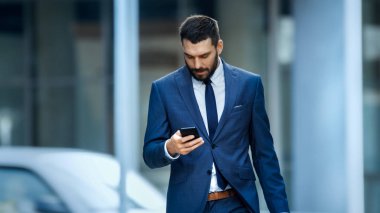 Başarılı bir iş adamı kullanır Smartphone büyük şehir iş bölgesinde sokakta yürürken.