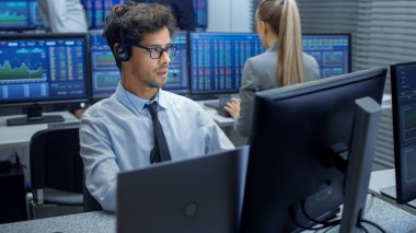 Stok tüccar bir kulaklık ile satış yapma. Arka plan Menkul Kıymetler Borsası Office ve grup tüccarlar çalışan iş istasyonlarında.