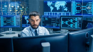 Monitoring Room Technical Operator Observes System Stability. He's Surrounded By Screens Showing Technical Data. clipart