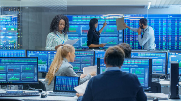 Многонациональная команда торговцев занята работой на фондовой бирже. Дилеры и брокеры покупают и продают акции на рынке. Мониторы отображают соответствующую инфографику, данные и цифры
.