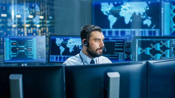 Sistem Denetim oda dağıtıcı görüşmeler kulaklık içine. Tesisin doğru çalışmalarını kontrol eder. Arka planda birden çok monitör teknik veriler göstermektedir..