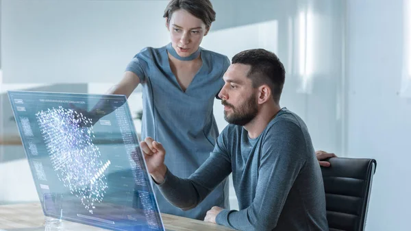 In the Near Future Male and Female Office Workers Discuss Neural Network, Artificial Intelligence Simulation Shown on Transparent Computer Display. Beautiful People Talking. Interactive Charts on the Screen.