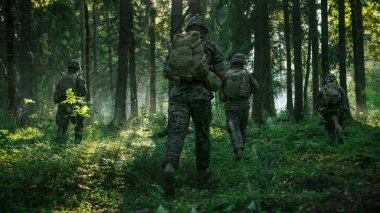 Tam donanımlı asker, düşman saldıran kamuflaj üniforma tüfek ateş için hazır. Aksiyon, yoğun Smokey orman yoluyla oluşumunda çalışan kadrosu askeri operasyonda. Arkadan görünüm görüntüleri.