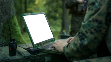 Yakın çekim asker kullanır askeri sınıf Laptop ile beyaz/yeşil perde. Askeri üste ormanın içinde arka planda kamufle.