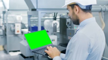Yakın çekim yeşil ekran Chroma anahtar şablon büyük Laptop için Mockup tutan mühendisi. Arka plan Modern fabrika ekipmanları.