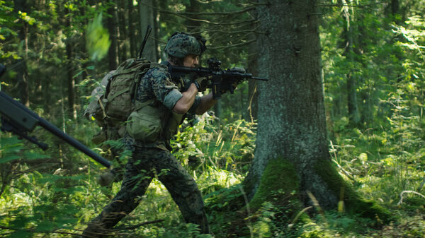 Squad of Fully Equipped Soldiers in Camouflage on a Reconnaissance Military Mission, Rifles in Firing Position. They're Running in Formation Through Dense Forest.