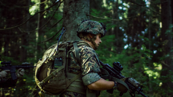 Fully Equipped Soldiers Wearing Camouflage Uniform Attacking Enemy, Rifles in Firing Position. Military Operation in Action, Squad Running in Formation Through Dense Forest. Side View Long Shot.