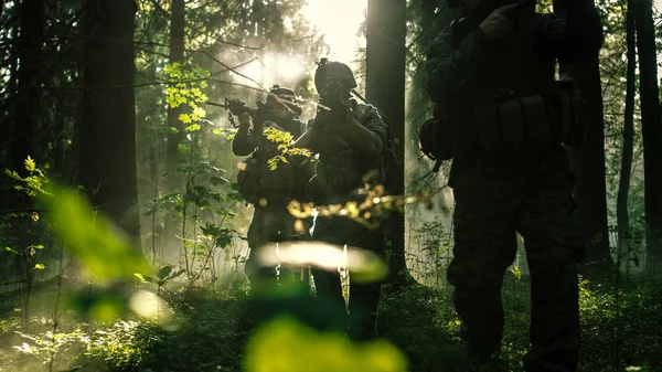 五队装备精良的士兵在侦察军事任务上伪装 步枪准备射击 他们正通过茂密的阳光森林进入队形 — 图库照片