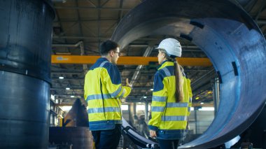 Erkek sanayi işçisi kask erkek şef mühendis metal işleme fabrikası'nın yeni projesi tartışıyorlar. Onlar ağır sanayi tesisi ortasında Stand.