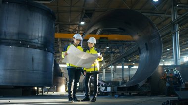 Erkek ve dişi Endüstri mühendisleri proje planları Surround boru hattı parçaları büyük ağır sanayi fabrikası üretim ortasında tarafından ayakta iken bak