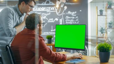 İki erkek geliştiriciler kişisel bilgisayar vardır yeşil Mock-up ekran ise proje ile ilgili konuşmak. Yaratıcı ajansı çalışıyorlar.