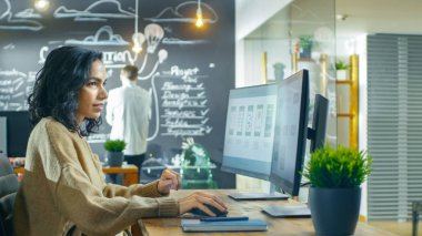 Güzel kadın mobil oyun uygulama geliştirici tel kafes tasarımı bir kişisel bilgisayarda çalışır. O ve onun arkadaşları yaratıcı Indie stüdyoda çalışmak.