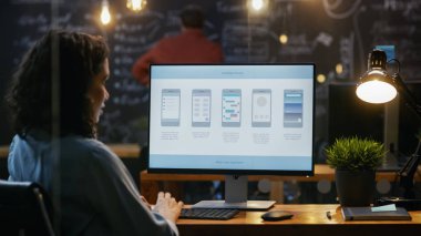 Güzel kadın Mobil Video oyun uygulama geliştiricisi masasının üstünde özel bilgisayar çalışıyor. Arka planda onun meslektaşım yaratıcı ofiste.