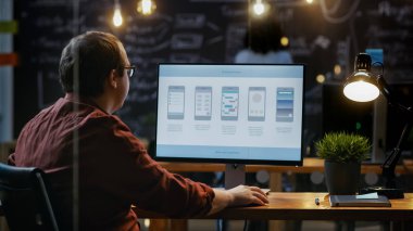 Erkek Mobil Video oyun uygulama geliştiricisi masasının üstünde özel bilgisayar çalışıyor. Arka planda onun meslektaşım yaratıcı ofiste.
