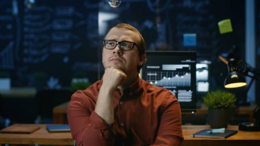 Genç ofis çalışanı düşünme ve ofisinde oturan.