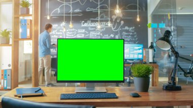 Kişisel bilgisayar Mock-up yeşil ekran monitör ofis masasında adam arka plan standları ile yaratıcı ofiste gündüz çalışıyor..