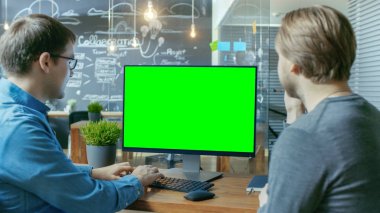 İki ofis çalışanları ilgili tartışma, Danışma standları proje var Mock-up ile kişisel bilgisayar ekran yeşil. Onlar yaratıcı ofis ortamında iş.