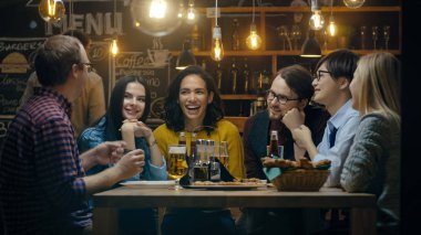 Farklı bir grup genç insan var eğlenceli Bar, görüşme, hikayeler ve şakalar söylüyorum. Çeşitli içki içiyorlar. Şık Hipster restoranda onlar.