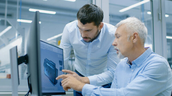 Industrial Designer Has Product Discussion with Senior Engineer While Working in CAD Program, Designing New Component. He Works on Personal Computer with Two Monitors.