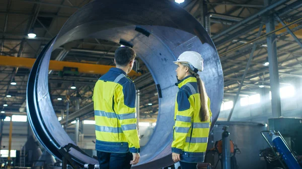 Erkek sanayi işçisi kask erkek şef mühendis metal işleme fabrikası'nın yeni projesi tartışıyorlar. Onlar ağır sanayi tesisi ortasında Stand.