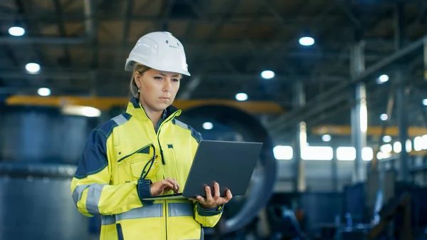 在重型工业制造厂 硬帽的女工业工程师使用笔记本电脑 在背景下各种金属制品工程零件的谎言 — 图库照片