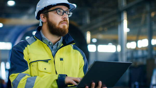 Промышленный инженер в твердой шляпе носить пиджак безопасности использует ноутбук. Работает на заводе тяжелой промышленности с различными металлургическими процессами
.