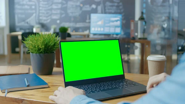 办公室男工在他的办公桌上工作的笔记本电脑与造型的绿色屏幕 在肩部特写镜头上方 在后台创作办公室 — 图库照片