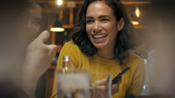 美丽的拉美裔妇女使用智能手机 一边说话 并与她的朋友在酒吧乐趣 他们笑 喝在时尚的时髦酒吧建立 — 图库照片