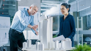 İki profesyonel erkek ve dişi mimari mühendis iş planları ve yapı modeli tasarımı için kentsel tasarım projesi.