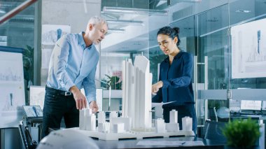 Mimari büro kadın mühendis getiriyor planlar içinde ve kıdemli mimar, onlar tartışmak proje gösterir. Bir yapı modeli kentsel planlamacılar çalışıyorlar.