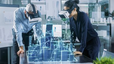 Male and Female Architects Wearing  Augmented Reality Headsets Work with 3D City Model. High Tech Office Professional People Use Virtual Reality Modeling Software Application. clipart