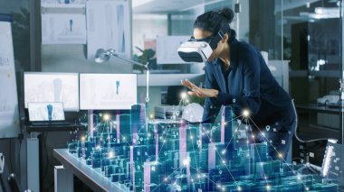Artırılmış gerçeklik kulaklık, jestlerle yapar giyen profesyonel kadın mimar için 3d şehir modeli istatistiklerini gösterir. High Tech Office kullanımı sanal gerçeklik yazılım uygulama modelleme.