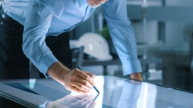 Üst düzey mimari mühendis berabere bina kavramı bir grafik Tablet ekran dikey dokunmatik ekran tablo. Temiz minimalist Office, beton duvarları tarafından planları.