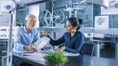 Deneyimli Otomotiv Tasarımcısı ve bir konsept araba modeli prototipin, o ve tasarım düzeltmeler yapma Perfecting ile kadın mühendis çalışır. Onlar bir şık, parlak, Modern ofis iş.