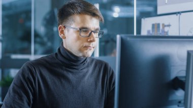 Genç erkek endüstri mühendisi bir kişisel bilgisayarda çalışır. Parlak Modern ofis yakışıklı zeki adam.