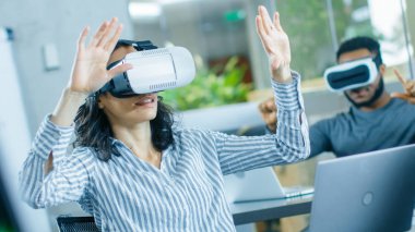 Kadın sanal gerçeklik mühendisi / sanal gerçeklik kulaklık giyen geliştirici onun meslektaşları ile içerik oluşturur. Yaratıcı genç artar ve karışık gerçeklik proje üzerinde çalışma insanlar.