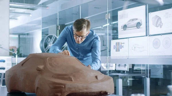Experience Automotive Designer with a Rake Sculpts Prototype Car Model from Plasticine Clay. He Works in a Modern Studio in a Major Automotive Company\'s Headquarters.