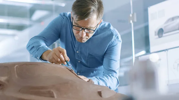 熊手と経験自動車デザイナーを Sculpts 粘土粘土から試作車 彼は主要な自動車の本社でモダンなスタジオで働く — ストック写真