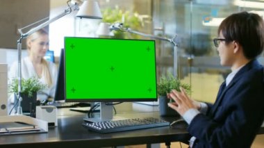 Office işadamı yapar Video seslenmek üstünde özel bilgisayar Mock-up ile yeşil ekran. O alıcı ile görüşmeler ve etkin olarak Gesticulates.