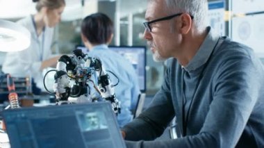 Üst düzey robot mühendisi Ses Kontrollü Robot yöneten, Laptop ekran yazılım öğrenme tekniği Makine kullanarak gösterir. Arka plan robotik Araştırma Merkezi Laboratuvarı.