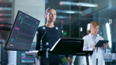Monitörü EKG okuma uzmanı arka planda bir koşu bandı üzerinde yürüyen bir kadın sporcu gösterilen en uygun hızda fiziksel aktivite kontrol egzersiz, denetlemektedir. Spor bilim Tema.