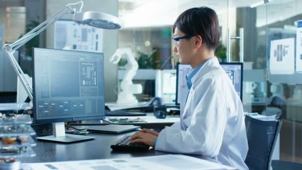 亚洲科学家坐在他的办公桌上 在他的台式计算机上进行复杂的编码和编程 基于机器人臂模型的计算机科学研究实验室 — 图库视频影像
