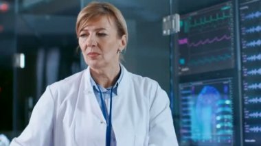 Kadın giyiyor Brainwave tarama kulaklık oturur bilim adamı ayarlar ise bir sandalyede cihaz görünüyor görüntüler. Modern beyin çalışma laboratuvar monitör Haritayı Eeg okuma ve beyin modeli.