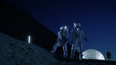 İki astronot uzay giysileri içinde yabancı gezegende gökyüzüne bakarak ayağa. Jeodezik kubbe ile arka plan Bankası '. Diğer dünyalar kolonizasyon ve uzay seyahat kavramı.