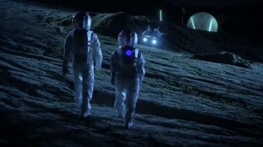 Gökyüzüne bakarak yabancı gezegende uzay giysileri bir yürüyüşle iki astronot shot takip. Jeodezik kubbe ile arka plan Bankası '. Diğer dünyalar kolonizasyon ve uzay seyahat kavramı.