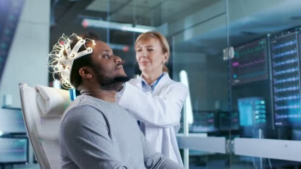 Mand Iført Hjernebølge Scanning Headset Sidder Stol Mens Videnskabsmand Justerer – Stock-video