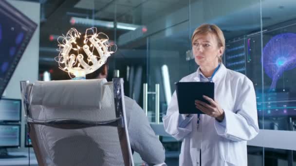 Man Wearing Brainwave Scanning Headset Sits Chair Sedangkan Scientist Tablet — Stok Video